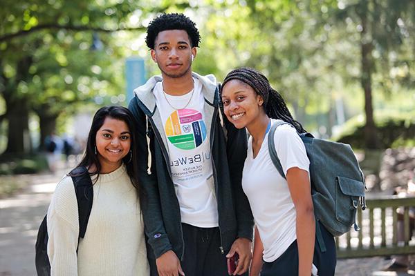 two female students with a male student in the middle wearing a BU Be Well shirt